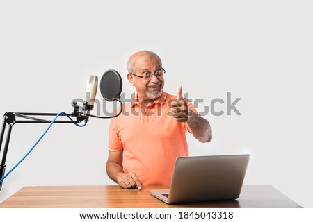 Confident Indian old man speaking in recording mic with filter while recording a video blog for his subscribers, looking at camera