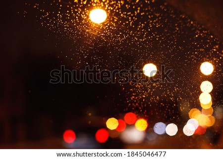 car windshield with raindrops, blurred background with glowing highlights