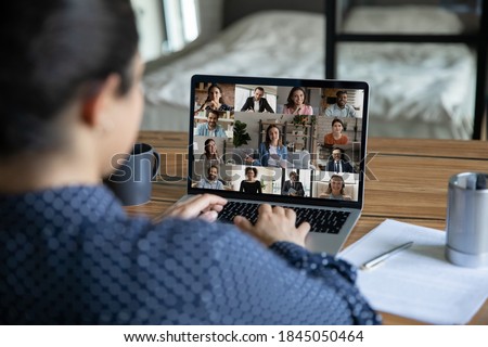 Rear view close up Indian businesswoman chatting with colleagues by video call, diverse business people on laptop screen, employees group discussing project, sharing ideas, online meeting, briefing Royalty-Free Stock Photo #1845050464