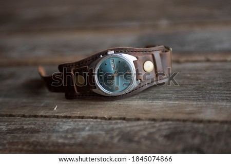 A watch with a blue dial and an old leather strap on a table made of old boards. Watch stock photos. 