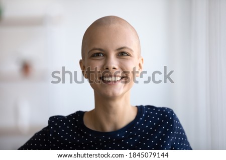 Head shot portrait smiling hairless attractive woman looking at camera, posing for photo, overjoyed bald young female struggling with cancer, oncology, healthcare and successful treatment concept