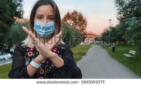 Woman in public park in protective mask with lettering No panic. Quarantine concept, pandemic influenza, coronavirus. Positive vibes