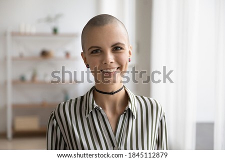 Head shot portrait smiling hairless woman with stylish makeup looking at camera, creative happy attractive young female designer or artist with accessory on neck, posing at home for profile picture
