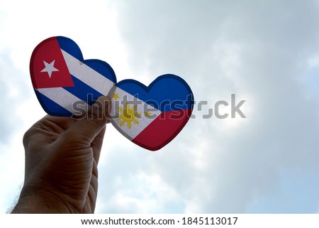Hand holds a heart Shape Cuba and Philippines flag, love between two countries
