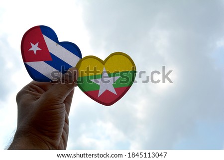 Hand holds a heart Shape Cuba and Myanmar flag, love between two countries