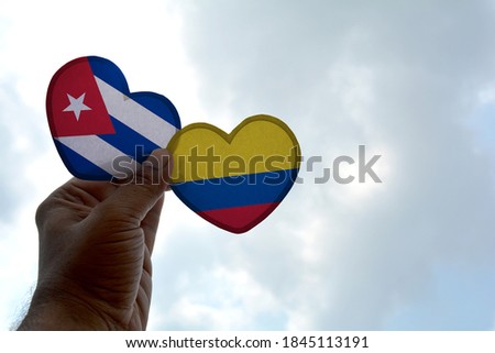 Hand holds a heart Shape Cuba and Colombia flag, love between two countries