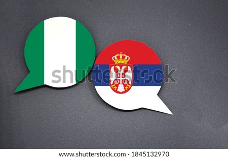Nigeria and Serbia flags with two speech bubbles on dark gray background