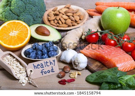 Healthy food, clean eating selection: fruit, vegetable, seeds, superfood, cereals, leaf vegetable on wooden background with tag "healthy food"