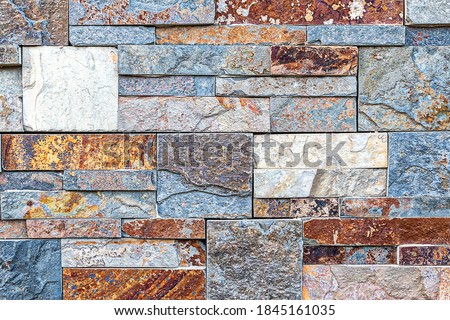 A wall made up of medium to large colored stones in a detailed view of the surface structure. Detailed view in excellent quality. For your graphic projects