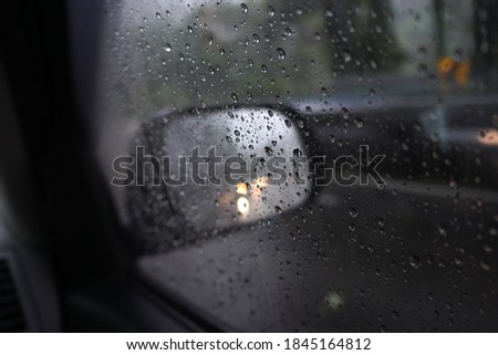 Blurred image of road traffic in rainy day with rain drop on car side view mirror