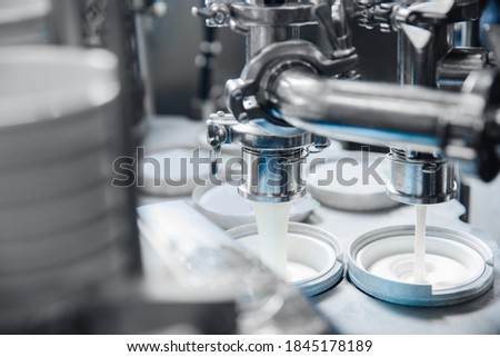 Automated filling of yoghurt into packages. Food production, dairy plant. Royalty-Free Stock Photo #1845178189