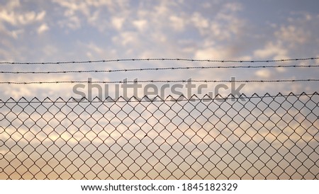 fence with barbed wire against sunset Royalty-Free Stock Photo #1845182329