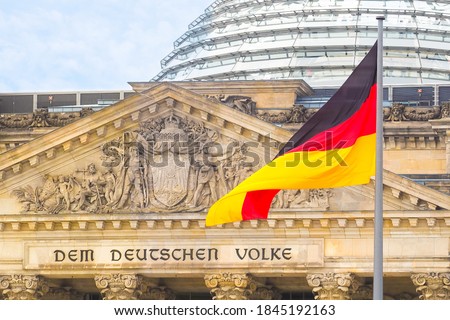 German flag on a background Reichstag building. The seat of the German Parliament or Bundestag, Berlin Mitte district. Inscription in German: To the German People Royalty-Free Stock Photo #1845192163