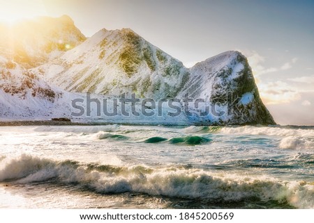 Spectacular beach in Arctic Norway on Lofoten islands named Unstad beach, the iconic place of Polar surfing. Amazign landscapes of seascapes. Snowy rock in background. Spring seasonal scenery.