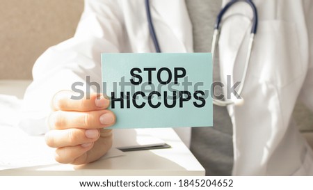 Doctor holding a paper plate with text STOP HICCUPS, medical concept