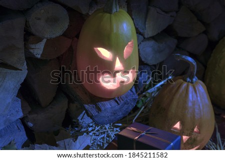 Orange glowing halloween pumpkin on background of stacked firewood with gifts