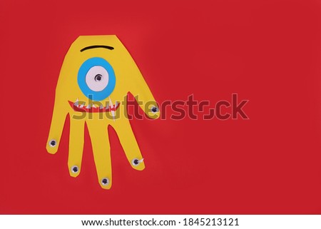 Funny yellow hand shaped monster on red background, top view with space for text. Halloween decoration