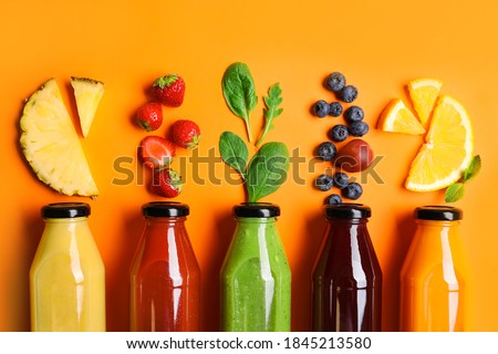 Flat lay composition with bottles of delicious juices and fresh ingredients on orange background Royalty-Free Stock Photo #1845213580