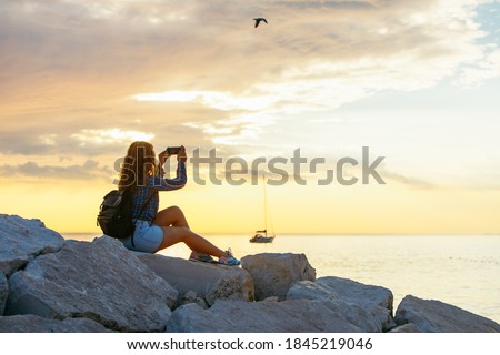 woman with backpack looking on sunset over the sea