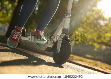 Woman riding electric kick scooter outdoors, closeup Royalty-Free Stock Photo #1845222493