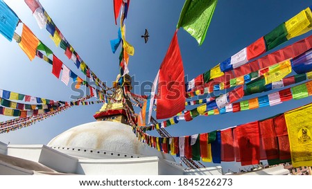 The Bouddhanath Temple in Kathmandu, Nepal. The temple has many colourful prayer flags with 'om mani padme hum' mantra written on them attached to it's golden rooftop. Spirituality and meditation. Royalty-Free Stock Photo #1845226273