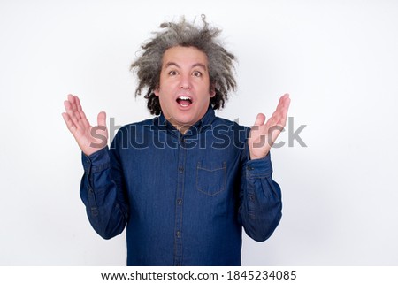 Surprised terrified Handsome mature caucasian man with afro grey hair standing over isolated white background Gestures with uncertainty, stares at camera, puzzled as doesn't know