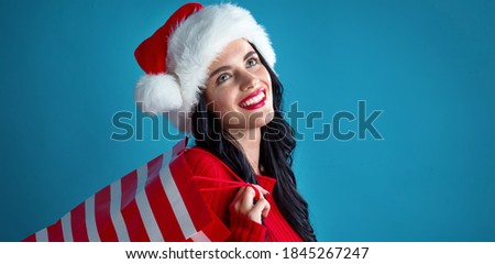 Young woman with santa hat holding a shopping bag on a dark blue background