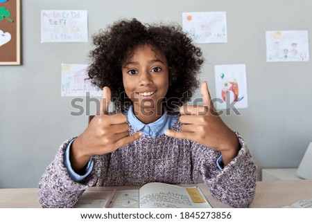 Happy african deaf mute kid school girl learning online class on laptop looking at webcam communicating by video conference call using sign language showing play gesture on virtual therapy, headshot. Royalty-Free Stock Photo #1845273856