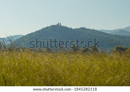 Picture of sveta ana church in the distance on top of the hill with a view between the green meadows.