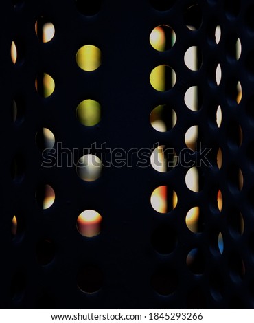 Vertical image. Perforated circles pattern with vivid colors in the background.