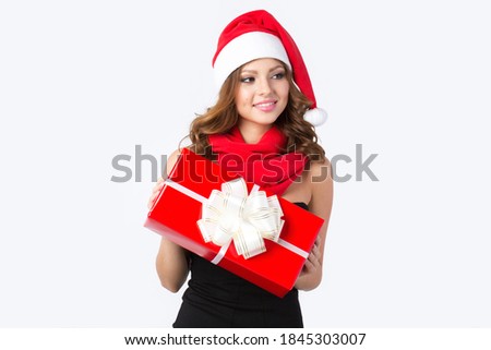 Beautiful smiling woman in Santa hat with a red gift box in her hands on a white background.