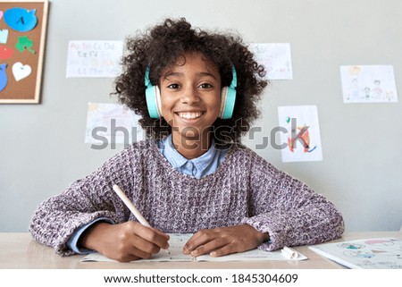 Happy african american kid child girl wearing headphones looking at web cam talking with remote teacher on distance learning video conference call chat class, headshot zoom portrait, webcam view. Royalty-Free Stock Photo #1845304609
