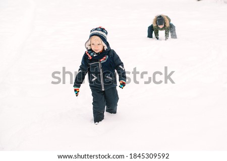 Happy kids playing snowballs game. Little brothers having fun together in winter park. Happy childhood. Winter holidays. Children play with snow in the forest.
