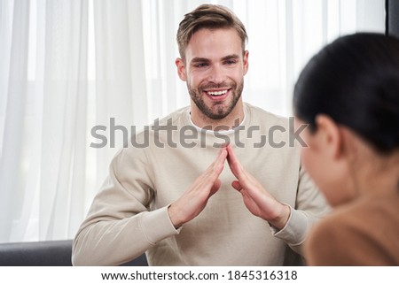 Our house. Young handsome man telling something about their house while showing symbols with hands. Man talking with deaf wife using visual-manual gestures. Focus on man. Deaf people concept image Royalty-Free Stock Photo #1845316318