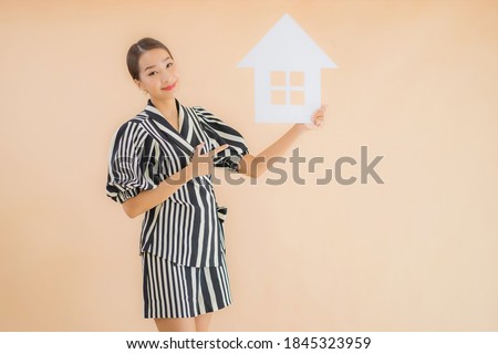 Portrait beautiful young asian woman show home or house paper sign on brown background