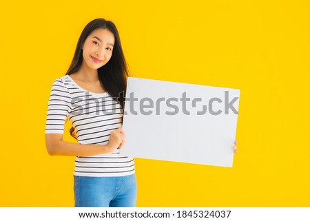 Portrait beautiful young asian woman show empty white billboard sign on yellow isolated background