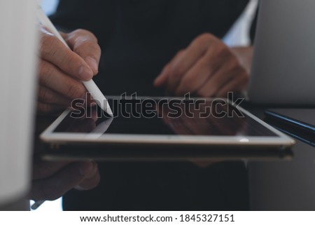 Business and digital technology concept. Business man using  digital tablet and stylus pen, working on laptop computer in modern office. Graphic designer using digital pen on design project, close up