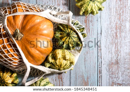 Thanksgiving background, composition with autumn pumpkins in shopping eco-friendly bag on wooden background. Autumn holiday, pumpkin harvest. Seasonal vegetables. Zero waste. Healthy natural food.