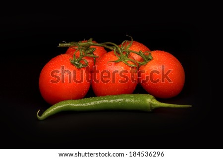 Tomatoes and chilli pepper on black background 