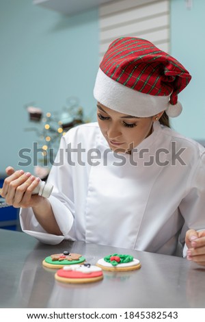 woman in the kitchen decorating Christmas cookies with a cake background