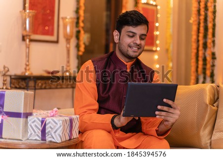 Young man in tradional wear sitting at home using laptop  Royalty-Free Stock Photo #1845394576