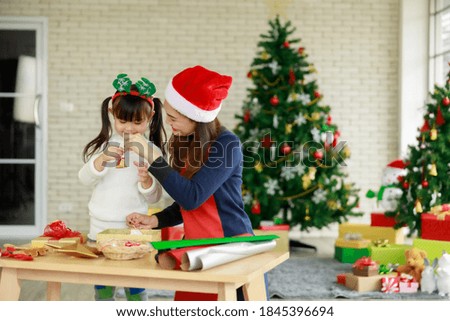 asian mother and daughter help each other in activities about Christmas tree at home