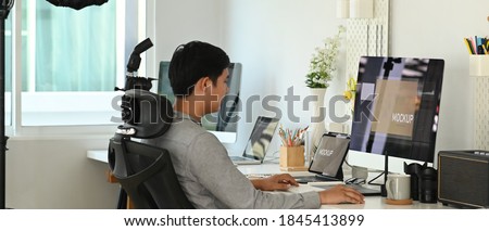 A professional photographer working in photo editing app or software on his personal computer.