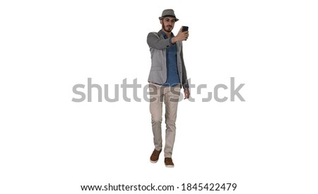 Arabian man in the casual clothes walking and making selfie on white background.