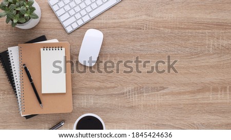 Top view wooden workspace office desk with computer and office supplies. Flat lay work table with blank notebook, keyboard, pen , smartphone and coffee cup. Copy space for your advertising content.
