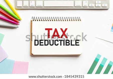 businesman hold notepad with text TAX DEDUCTIBLE. White background. Business