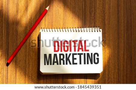 Red pen and notepad with text DIGITAL MARKETING in the white background