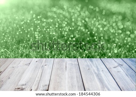 Fresh spring green grass with green bokeh and sunlight and wood floo