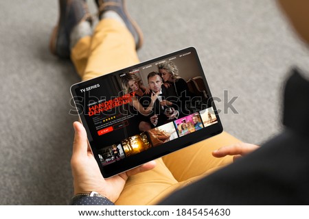 Man looking TV series and movies via streaming service on his digital tablet Royalty-Free Stock Photo #1845454630