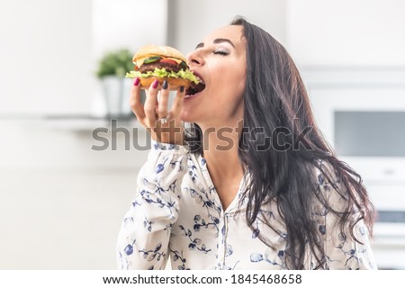 Enjoying a bite of a hamburger by a female.